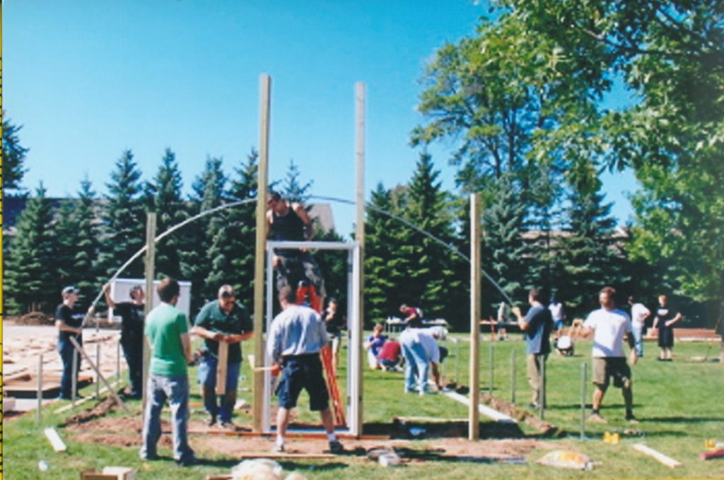 A group of people working together constructing a hoop house (greenhouse) structure